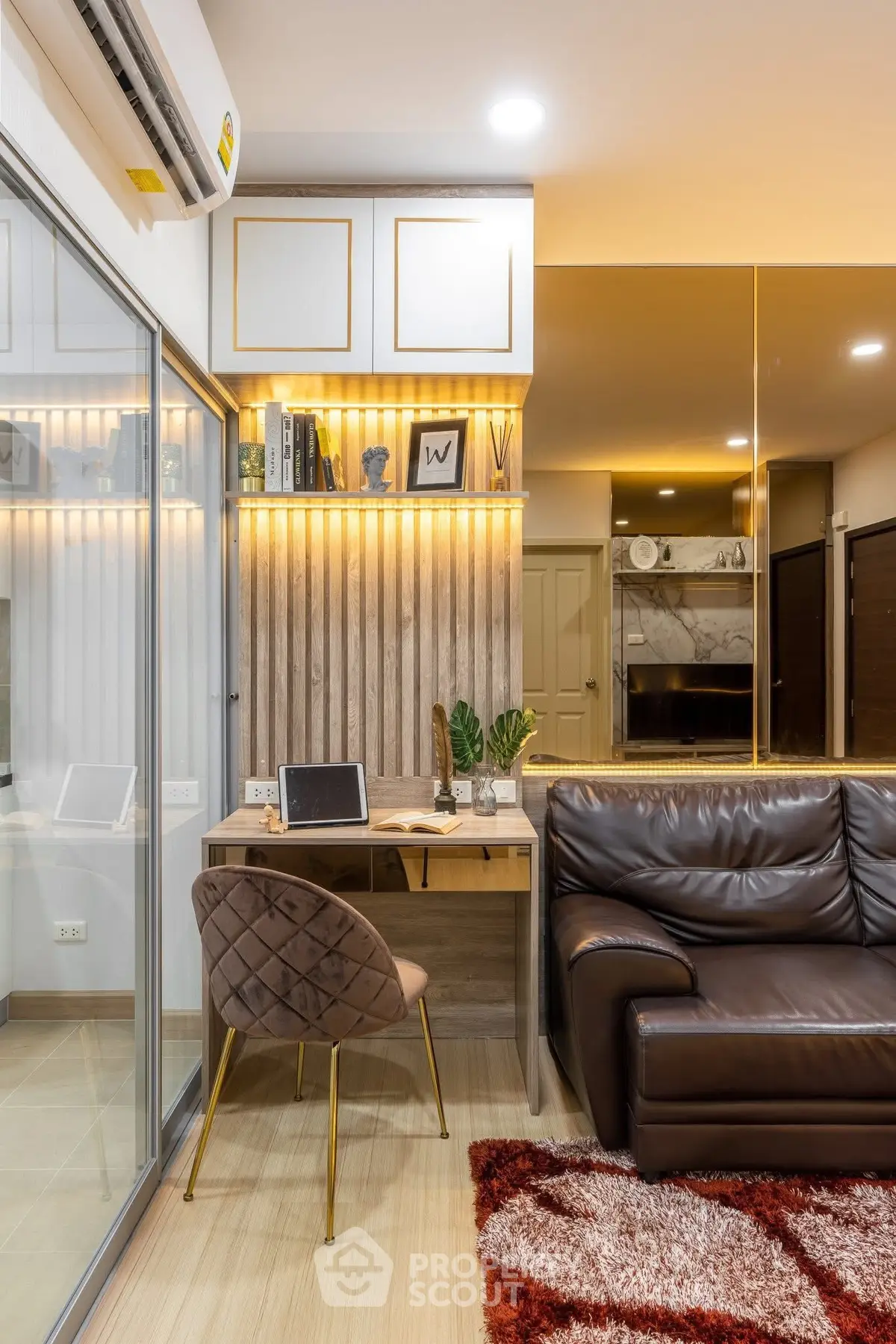 Modern living room with stylish decor, leather sofa, and cozy workspace in a contemporary apartment.