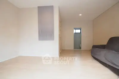 Spacious minimalist living room with wooden flooring and neutral tones, perfect for modern living.