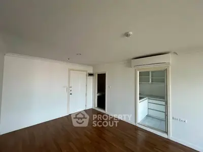 Spacious empty room with wooden flooring and air conditioning, ideal for customization.