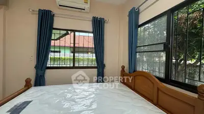 Cozy bedroom with large windows and air conditioning, perfect for comfort and relaxation.