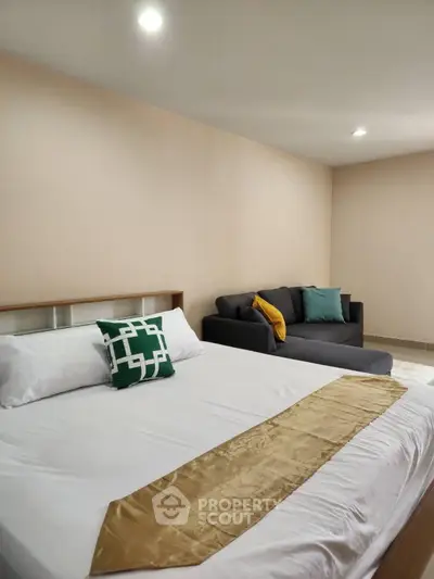 Spacious bedroom with modern decor and cozy seating area, perfect for relaxation and comfort.