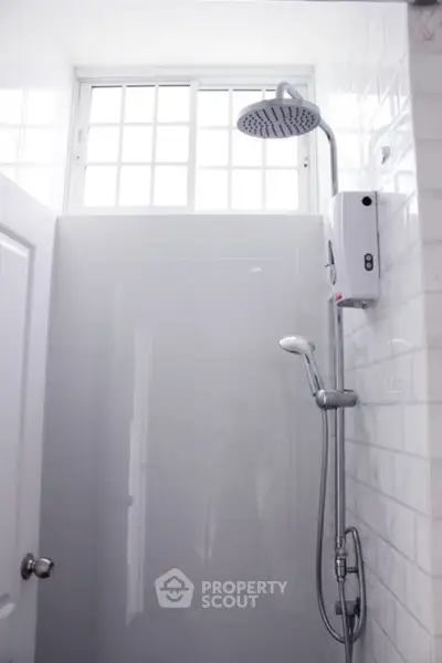 Modern bathroom shower with sleek white tiles and rainfall showerhead
