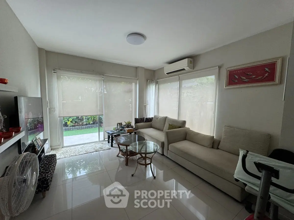 Spacious living room with modern furniture and large windows overlooking garden.
