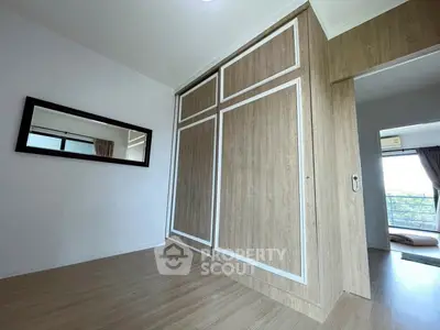 Spacious bedroom with wooden sliding wardrobe and large mirror