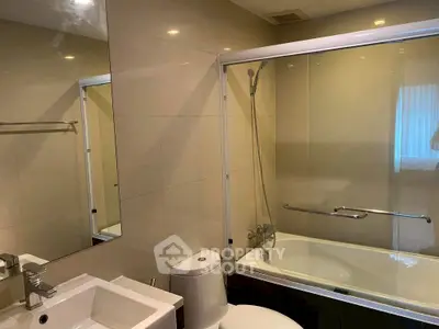 Modern bathroom with sleek fixtures and glass-enclosed bathtub