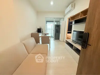 Modern living room with beige sofa, TV, and balcony access in a stylish apartment.