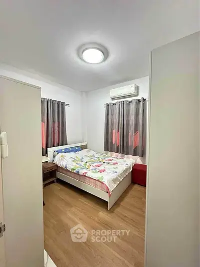 Cozy bedroom with wooden flooring and modern air conditioning unit.
