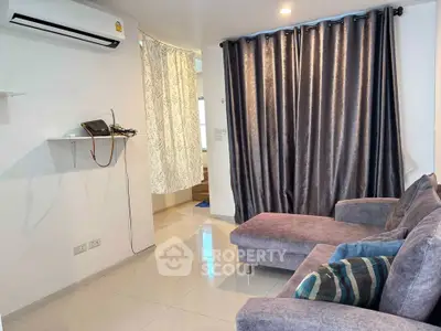 Cozy living room with modern sofa and air conditioning, featuring elegant curtains and polished tile flooring.