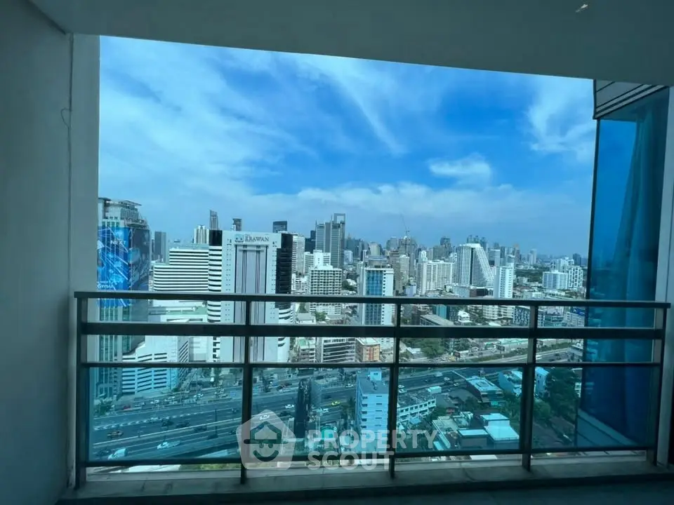 Stunning cityscape view from a modern balcony with glass railing.