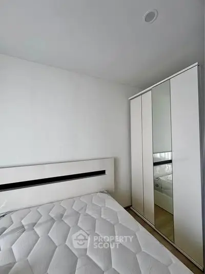 Modern minimalist bedroom with sleek white wardrobe and stylish bed frame.