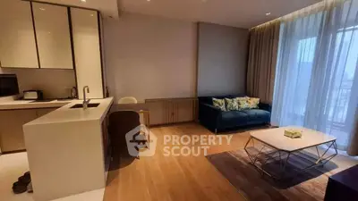 Modern living room with open kitchen, featuring sleek design and natural light.
