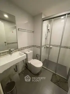 Modern bathroom with sleek fixtures and glass shower enclosure in a contemporary apartment.