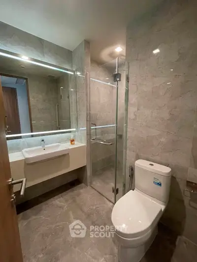 Modern bathroom with glass shower and sleek fixtures in luxury apartment