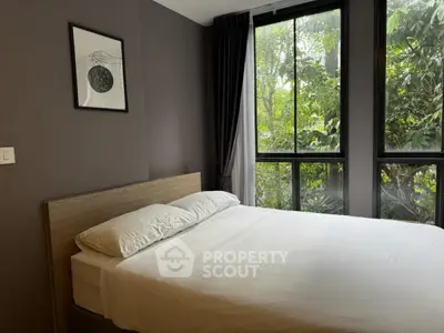 Modern bedroom with large windows and lush greenery view