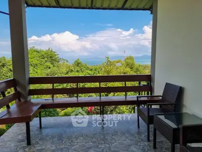 Stunning balcony with panoramic views of lush greenery and distant ocean, perfect for relaxation.