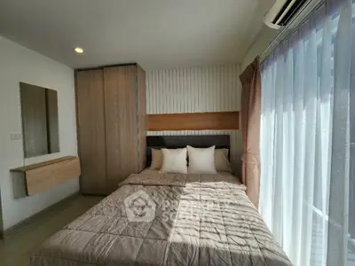 Cozy bedroom with modern decor and ample natural light from large window.