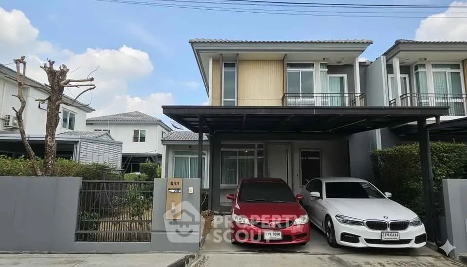 Modern two-story house with carport and two cars parked in driveway.
