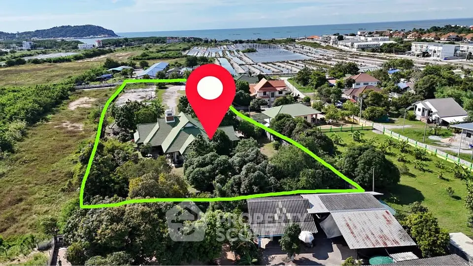 Aerial view of a spacious property with lush greenery and ocean view, ideal for serene living.