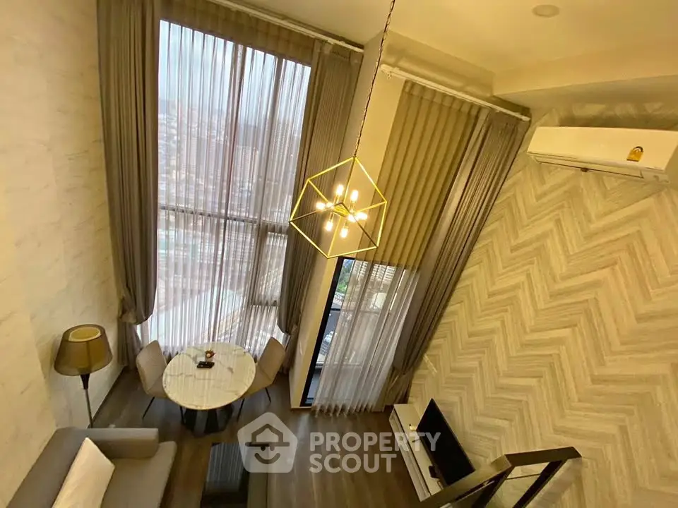Modern loft-style living room with high ceilings and large windows, featuring elegant decor and a cozy dining area.