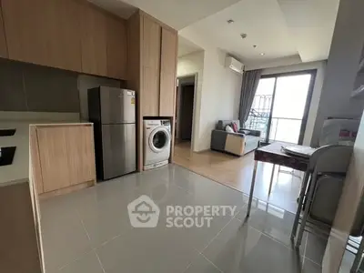 Modern apartment interior with kitchen and living area, featuring sleek appliances and bright natural light.