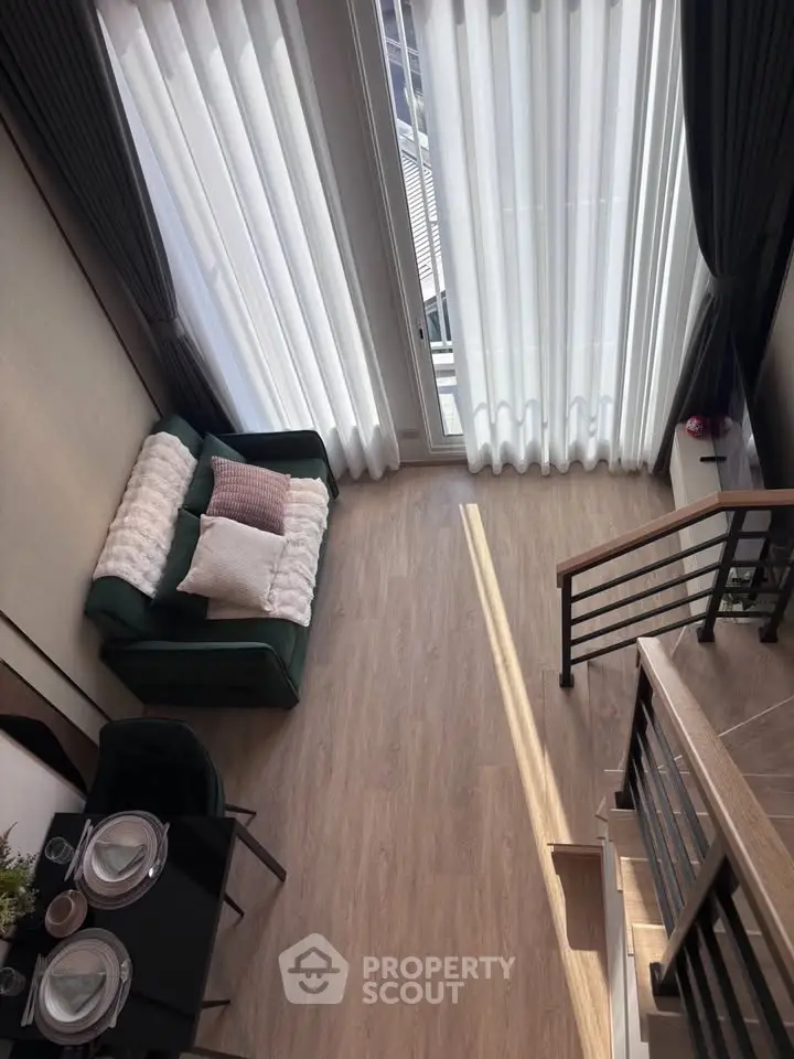 Modern loft-style living room with high ceilings, large windows, and stylish decor.