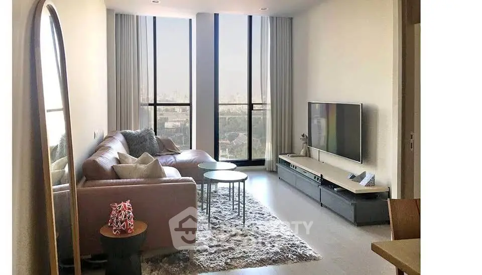 Modern living room with large windows and stylish furniture offering a stunning city view.