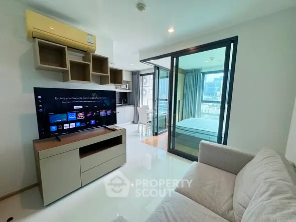 Modern living room with TV and sliding glass doors to bedroom in a stylish apartment.