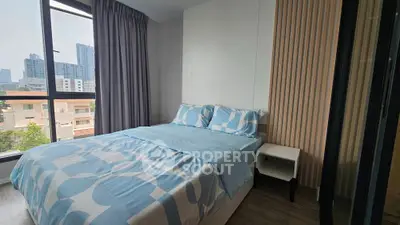 Modern bedroom with city view, featuring stylish decor and large windows for natural light.