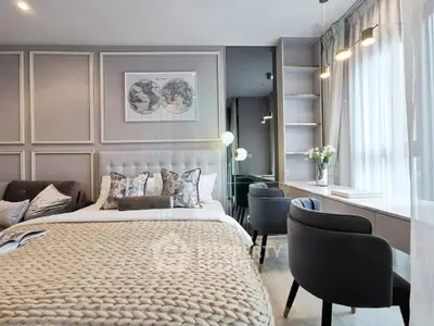 Luxurious bedroom with elegant decor and natural light, featuring a cozy bed and stylish seating area.