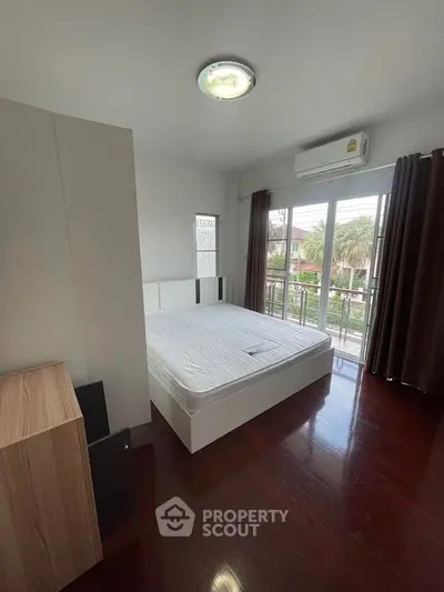 Spacious bedroom with large windows and garden view, featuring modern furnishings and air conditioning.