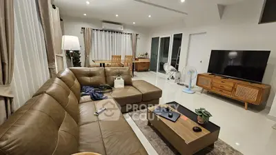 Spacious modern living room with leather sectional sofa and large TV, perfect for relaxation and entertainment.