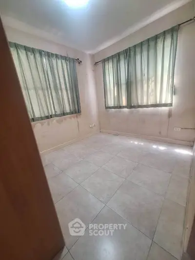 Spacious empty room with tiled flooring and large windows, ideal for customization.