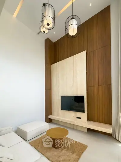 Modern living room with high ceiling, stylish lighting, and wooden accent wall featuring a mounted TV.