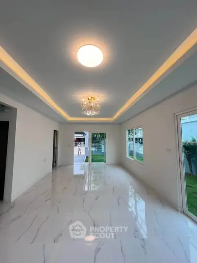 Spacious modern living room with elegant lighting and large windows overlooking garden
