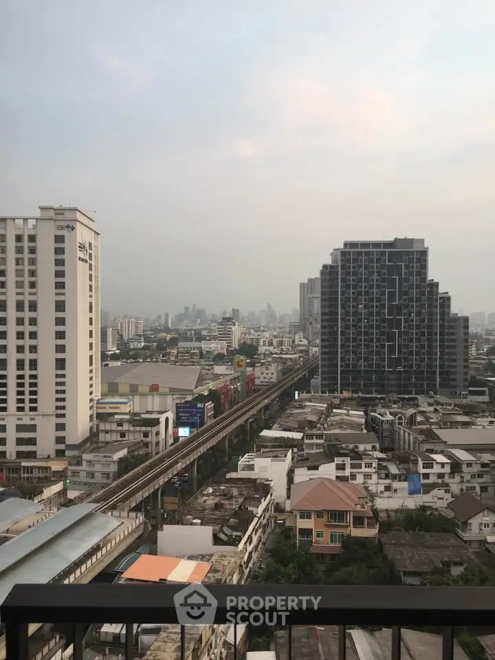 Stunning cityscape view from high-rise balcony overlooking urban skyline and train tracks.