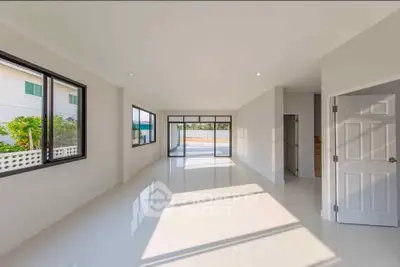 Spacious sunlit living room with large windows and glossy floors in modern home.