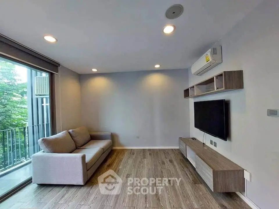 Modern living room with sleek design, featuring a comfortable sofa, wall-mounted TV, and large window with balcony view.