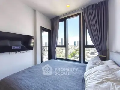 Modern bedroom with large windows offering stunning city views and a wall-mounted TV.