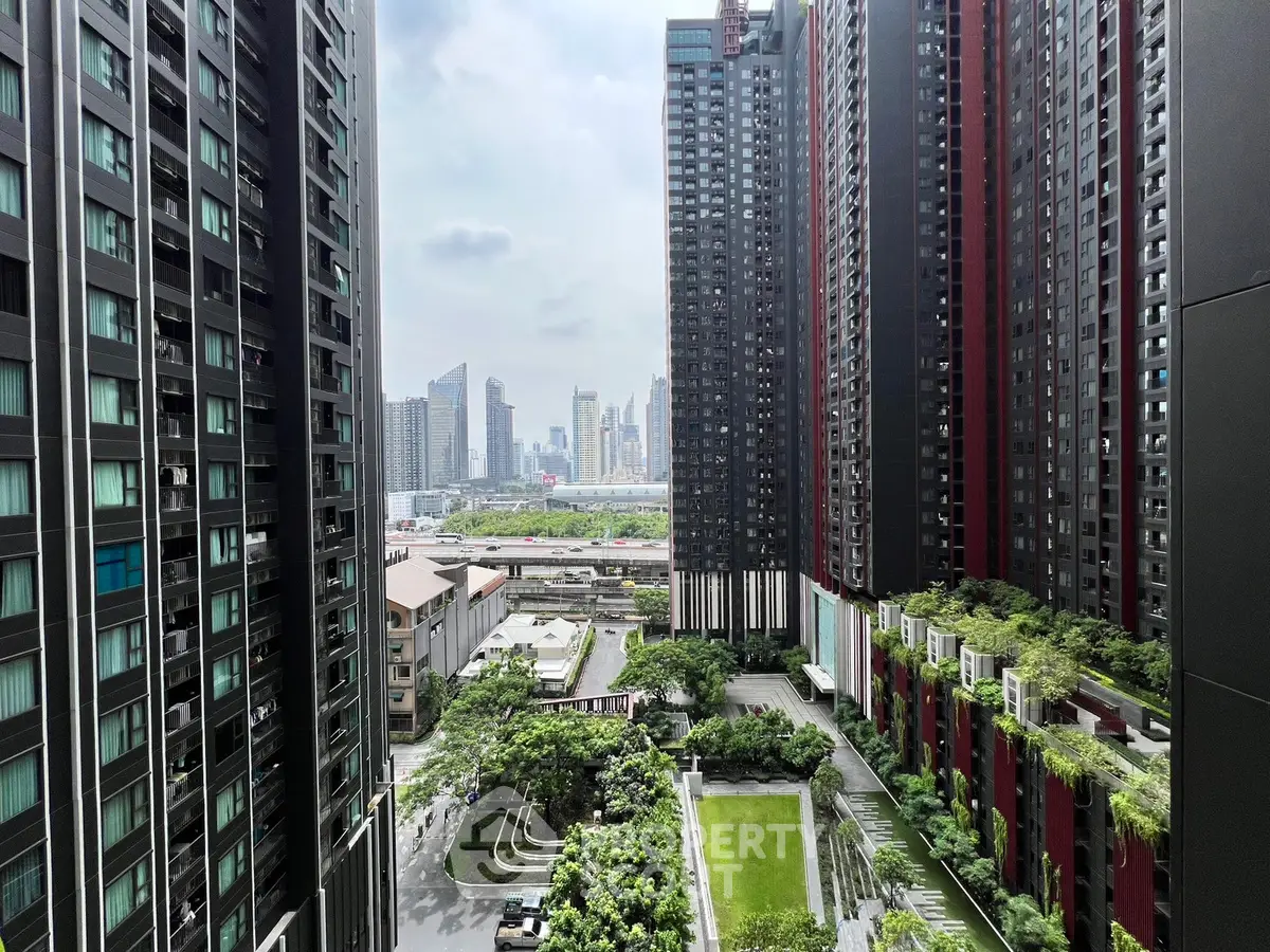 Stunning cityscape view from modern high-rise apartment complex with lush green gardens.