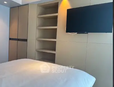 Modern bedroom with built-in shelves and wall-mounted TV, featuring sleek design and cozy ambiance.