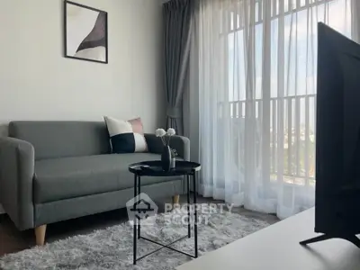 Modern living room with stylish sofa, elegant decor, and large window offering natural light and scenic view.