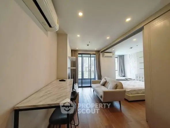 Modern open-plan living room with stylish furniture and balcony access in a contemporary apartment.