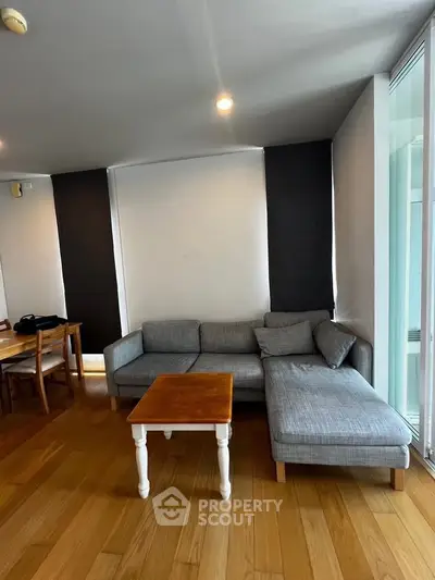 Spacious living room with modern gray sectional sofa and wooden flooring, perfect for relaxation.