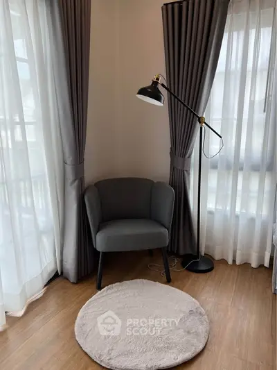 Cozy reading nook with armchair and floor lamp by large windows in modern home.
