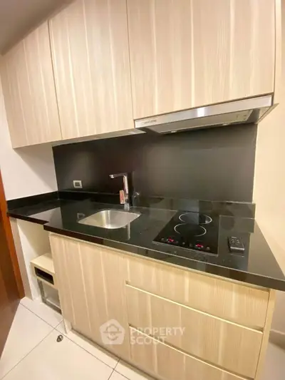 Modern compact kitchen with sleek cabinetry and electric cooktop