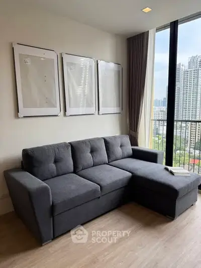 Modern living room with stylish gray sofa and city view from large windows.