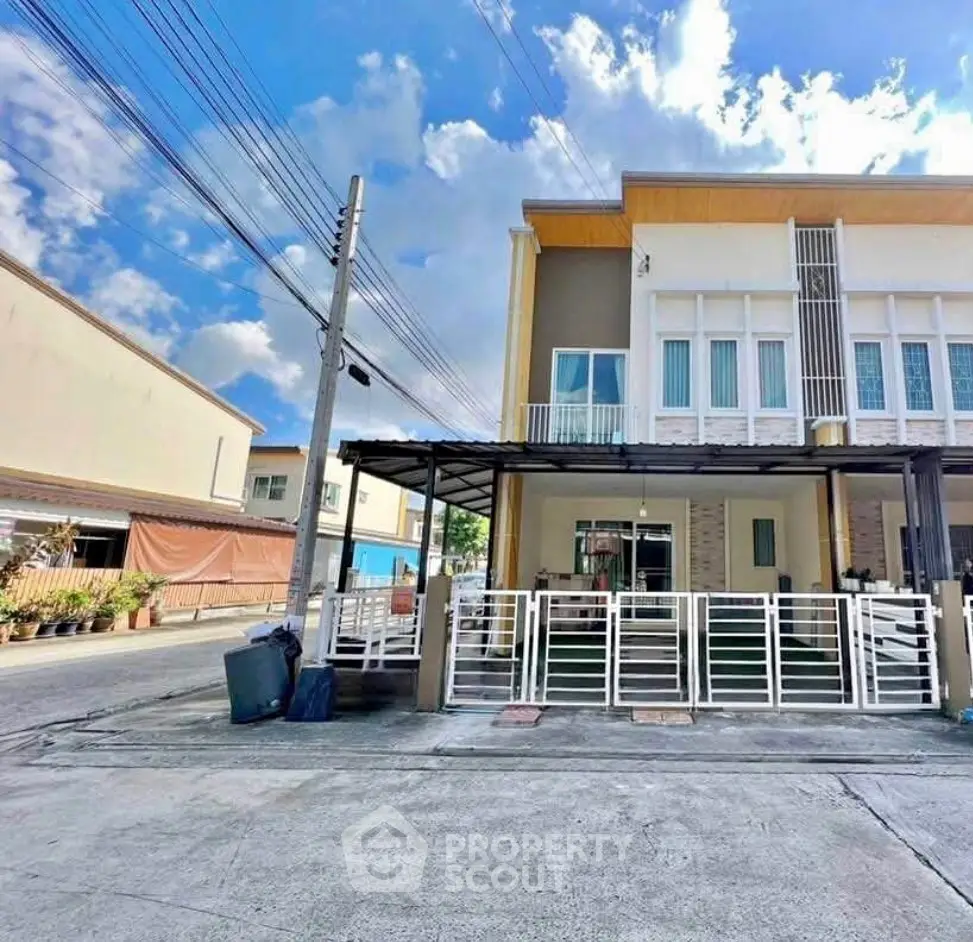 Modern townhouse exterior with gated entrance and clear blue sky