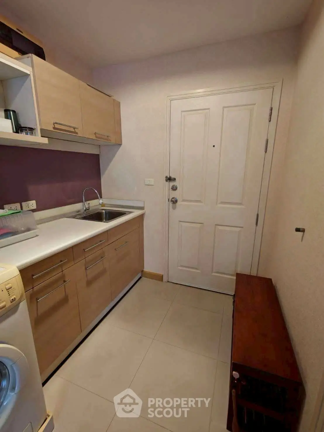 Compact kitchen with modern cabinetry and washing machine in cozy apartment.