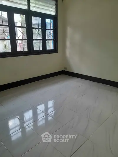 Spacious empty room with large windows and tiled flooring, perfect for customization.