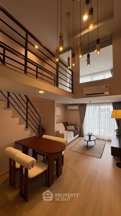 Stunning duplex living room with modern decor and high ceilings, featuring elegant lighting and a cozy seating area.